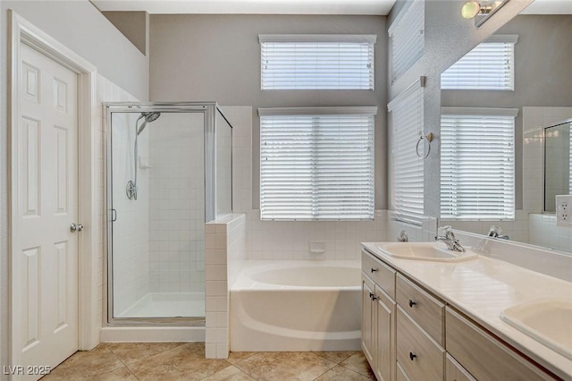 full bathroom featuring a bath, a stall shower, tile patterned flooring, and a sink