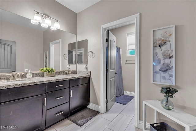 full bathroom with double vanity, baseboards, and a sink