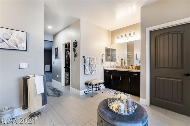 full bath featuring a spacious closet, baseboards, and vanity