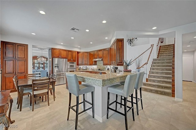 kitchen featuring a kitchen bar, visible vents, under cabinet range hood, and a peninsula