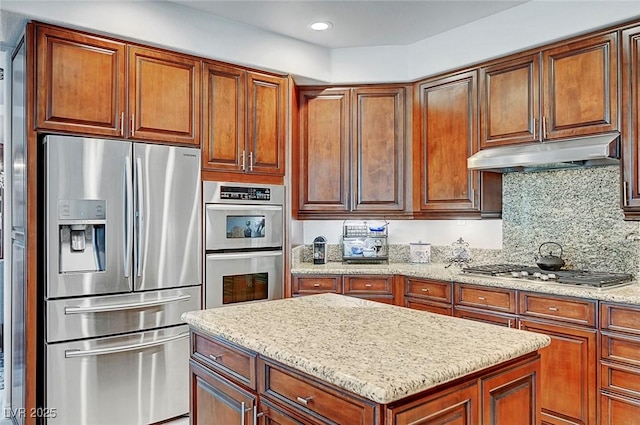 kitchen featuring decorative backsplash, a center island, light stone countertops, stainless steel appliances, and under cabinet range hood