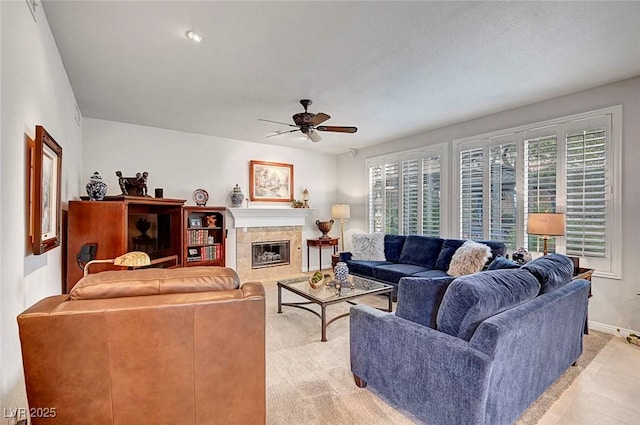 living room featuring ceiling fan, a fireplace, and baseboards