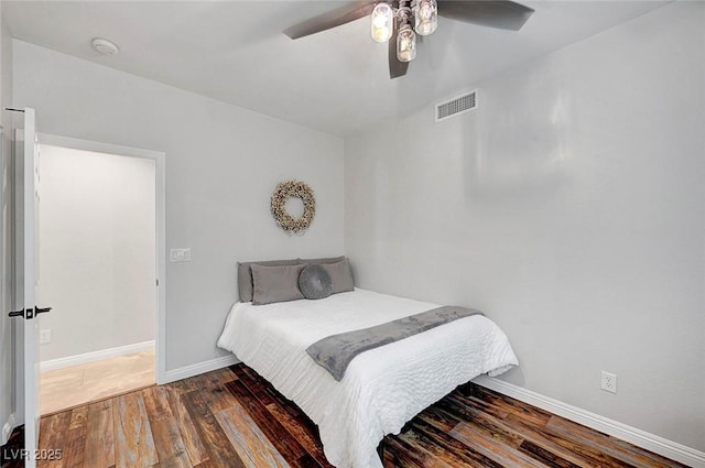 bedroom with a ceiling fan, wood finished floors, visible vents, and baseboards