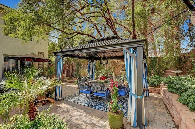 view of patio featuring outdoor dining area, fence, and a gazebo