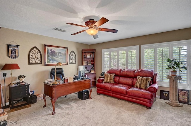 home office featuring carpet, visible vents, ceiling fan, and a textured ceiling