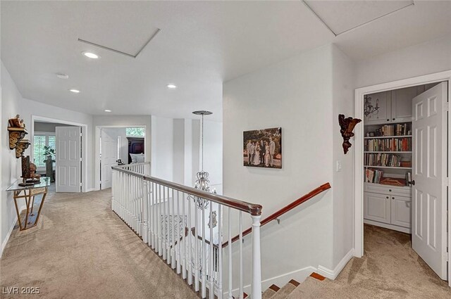 hall featuring attic access, light carpet, and an upstairs landing