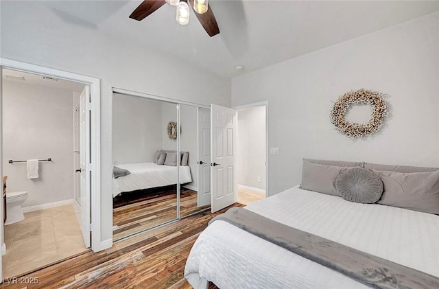 bedroom with a closet, light wood-style flooring, ceiling fan, ensuite bath, and baseboards