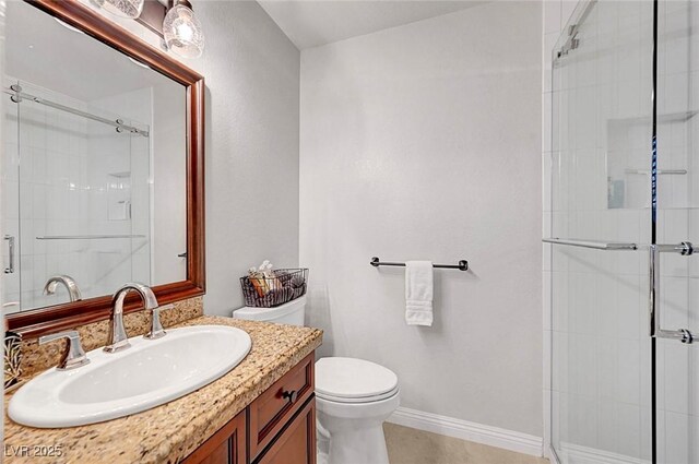 full bathroom with tile patterned flooring, toilet, vanity, baseboards, and a tile shower