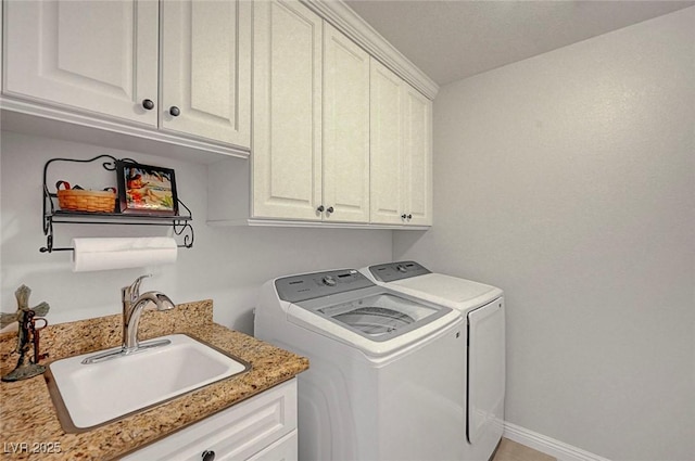 laundry area featuring cabinet space, a sink, baseboards, and separate washer and dryer