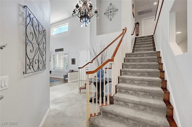 stairs featuring baseboards, visible vents, a notable chandelier, and a high ceiling