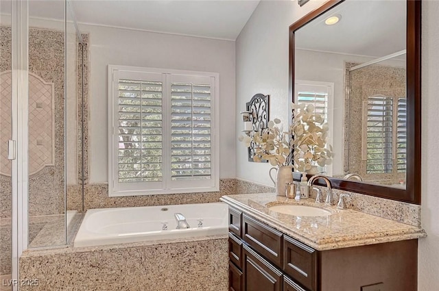 bathroom featuring a healthy amount of sunlight, a garden tub, a shower stall, and vanity