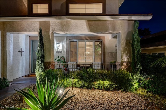 exterior entry at twilight featuring stucco siding