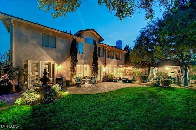 back of house with a yard, a patio, stucco siding, an outdoor hangout area, and fence