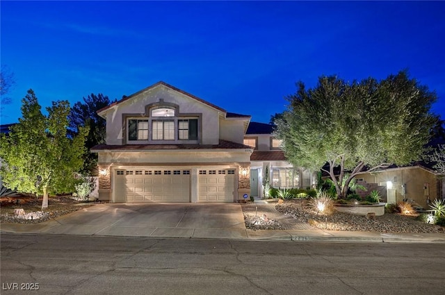 view of front facade featuring concrete driveway, an attached garage, and stucco siding