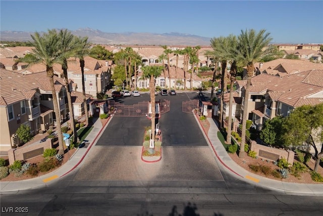 view of street featuring a gate, a residential view, a mountain view, and curbs