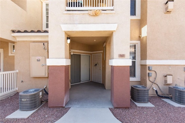 view of exterior entry featuring cooling unit and stucco siding