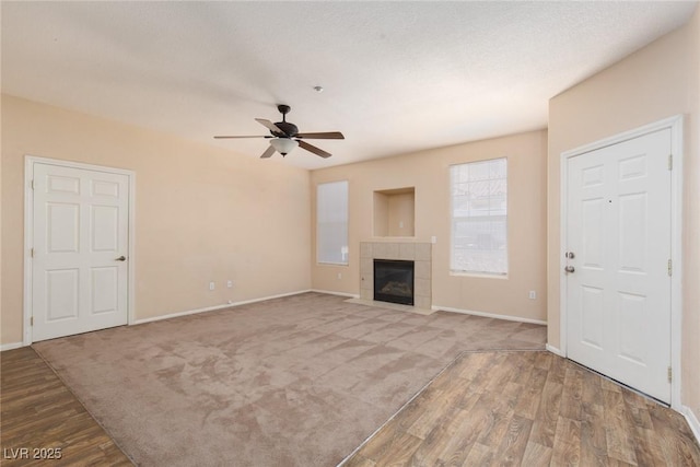 unfurnished living room with a ceiling fan, carpet, baseboards, and a tiled fireplace