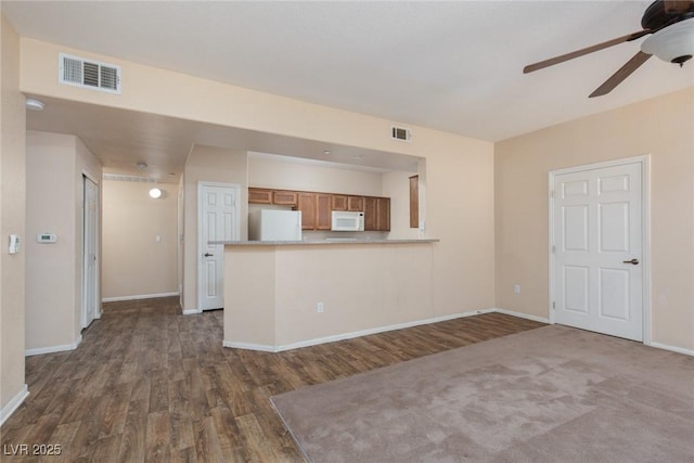 unfurnished living room featuring baseboards, visible vents, and dark wood finished floors