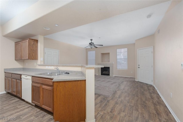 kitchen with light countertops, light wood-style flooring, a sink, dishwasher, and a peninsula