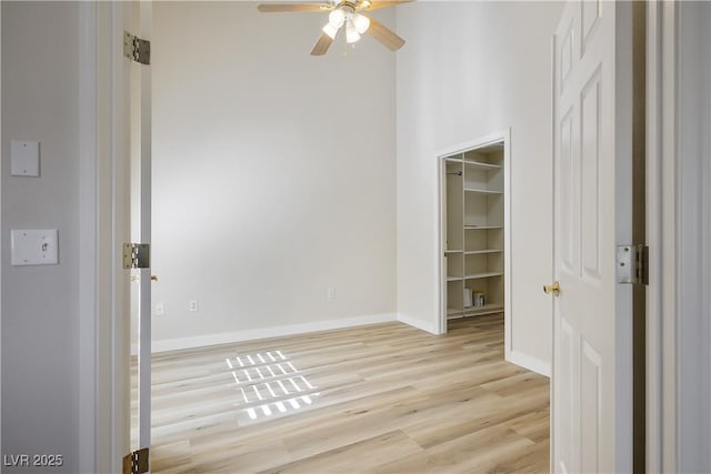 spare room with baseboards, ceiling fan, and light wood finished floors