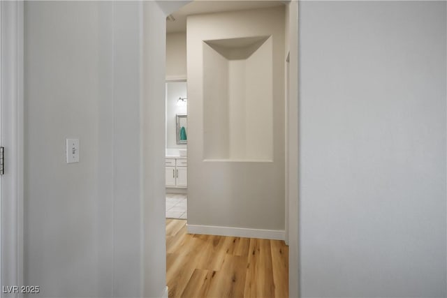 hall featuring light wood finished floors and baseboards