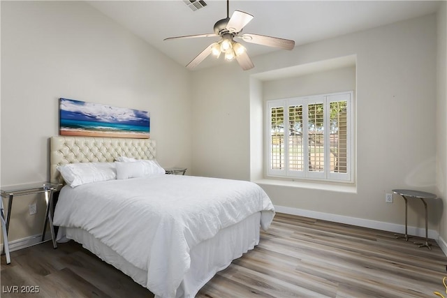 bedroom with a ceiling fan, visible vents, baseboards, and wood finished floors