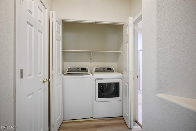 laundry room with laundry area, washing machine and dryer, wood finished floors, and a textured wall