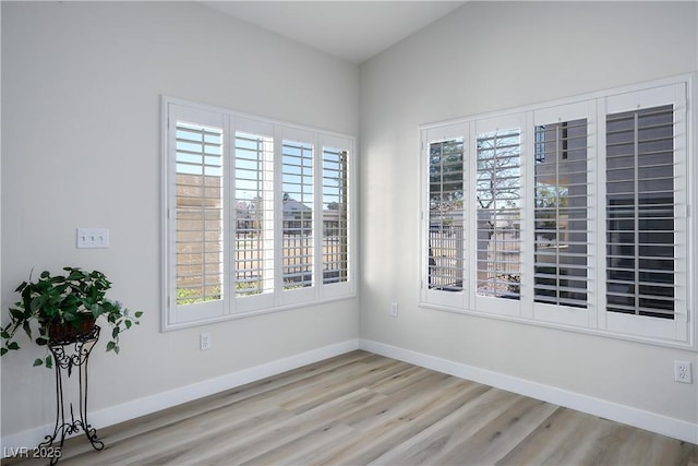 spare room featuring baseboards and wood finished floors