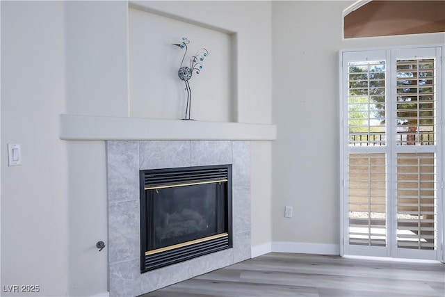 interior details with a fireplace, wood finished floors, and baseboards