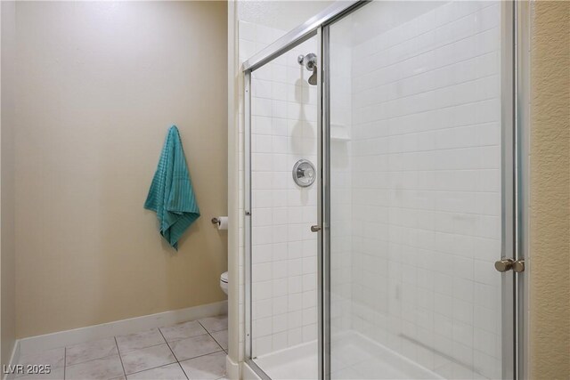 bathroom featuring baseboards, a shower stall, toilet, and tile patterned floors