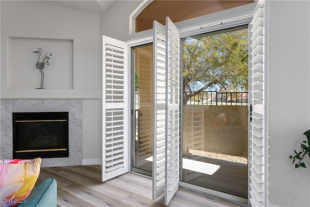 entryway with light wood-style flooring and a tiled fireplace