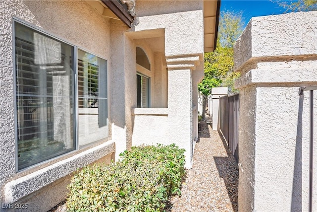 view of side of home with fence and stucco siding