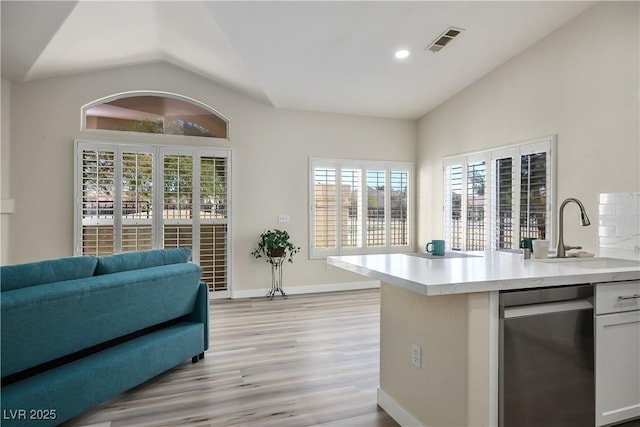 kitchen with a sink, visible vents, baseboards, vaulted ceiling, and light countertops