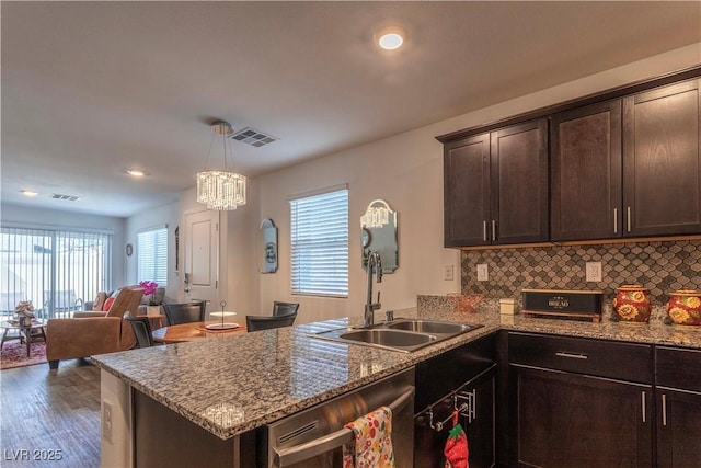 kitchen with dark brown cabinetry, a peninsula, a sink, visible vents, and dishwasher