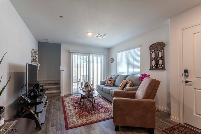 living room featuring stairs, wood finished floors, visible vents, and baseboards