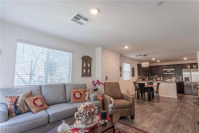 living room with dark wood finished floors, visible vents, and recessed lighting