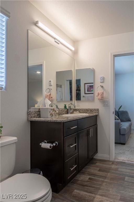 full bath featuring baseboards, vanity, toilet, and wood finished floors