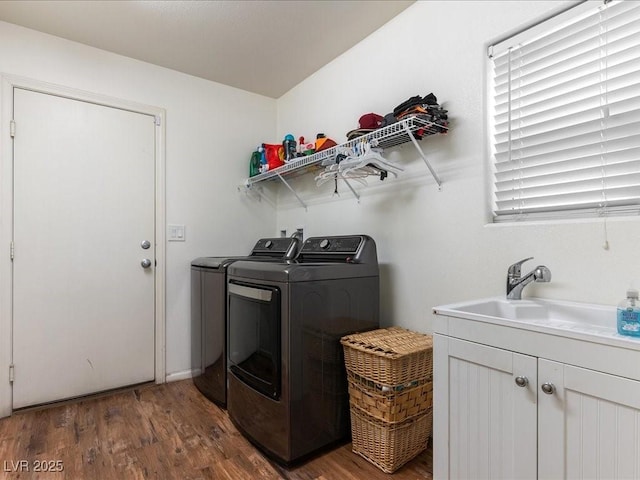 laundry area featuring a sink, separate washer and dryer, wood finished floors, and cabinet space