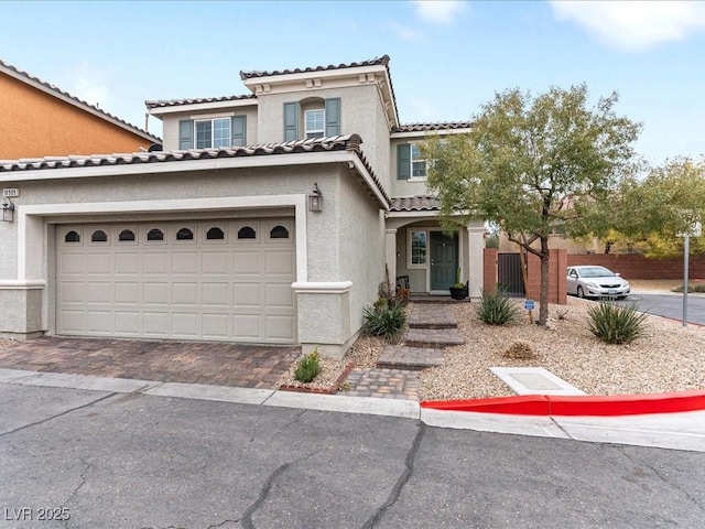 mediterranean / spanish home with a tile roof, decorative driveway, and stucco siding