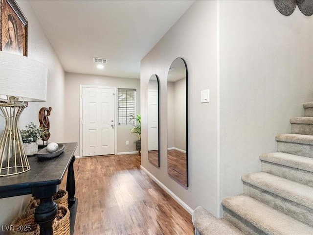 interior space featuring light wood-type flooring, visible vents, baseboards, and stairs