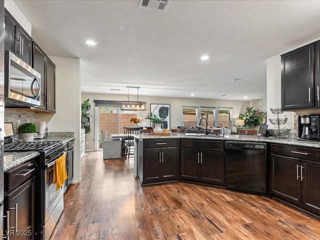 kitchen featuring stainless steel appliances, visible vents, decorative backsplash, dark wood-type flooring, and a sink