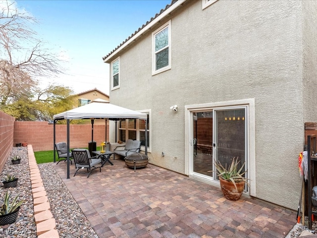 back of property with a patio, a fenced backyard, a tile roof, a gazebo, and stucco siding