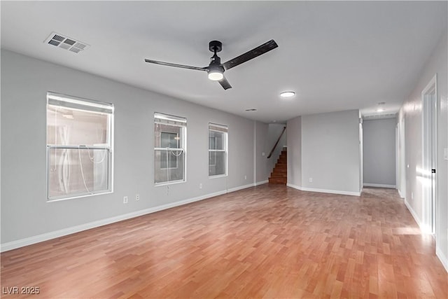 unfurnished room featuring ceiling fan, stairway, light wood-type flooring, and visible vents