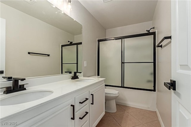 bathroom with double vanity, a sink, toilet, and tile patterned floors