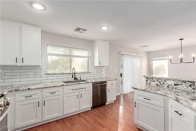 kitchen featuring visible vents, white cabinets, light wood-style flooring, stainless steel appliances, and a sink