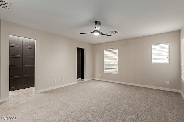 unfurnished room featuring light carpet, ceiling fan, visible vents, and a wealth of natural light