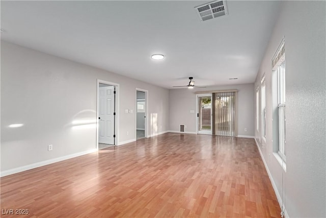 empty room with light wood-type flooring, visible vents, and baseboards