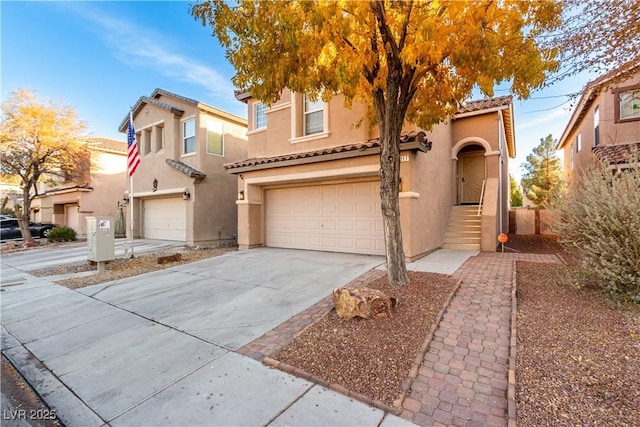 mediterranean / spanish house featuring driveway, a tiled roof, an attached garage, and stucco siding