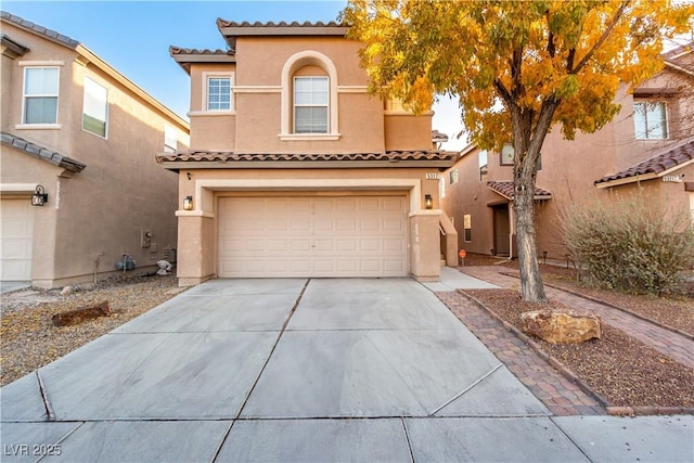 mediterranean / spanish home with concrete driveway, an attached garage, a tile roof, and stucco siding