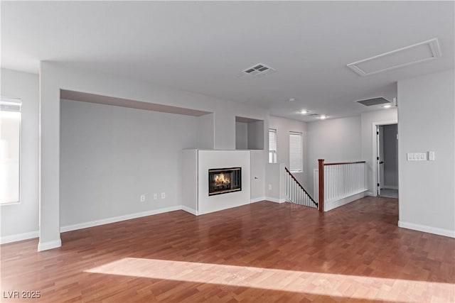 unfurnished living room with visible vents, baseboards, and wood finished floors